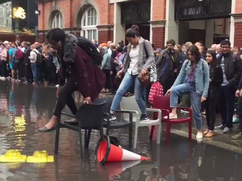 Stranded commuters make bridge of chairs to avoid flash floods near station